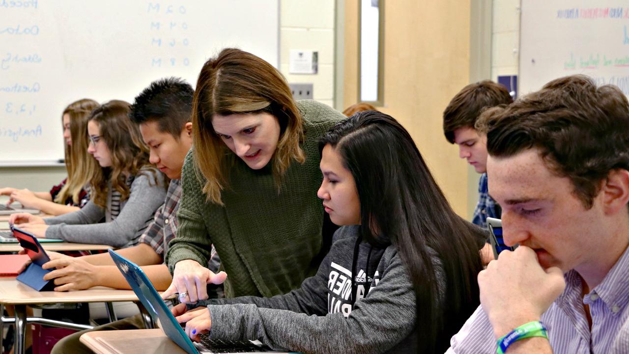 Teacher helping students in Chase Collegiate classroom